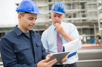 deux-hommes-casques-bleus-tablette-chantier-immeuble